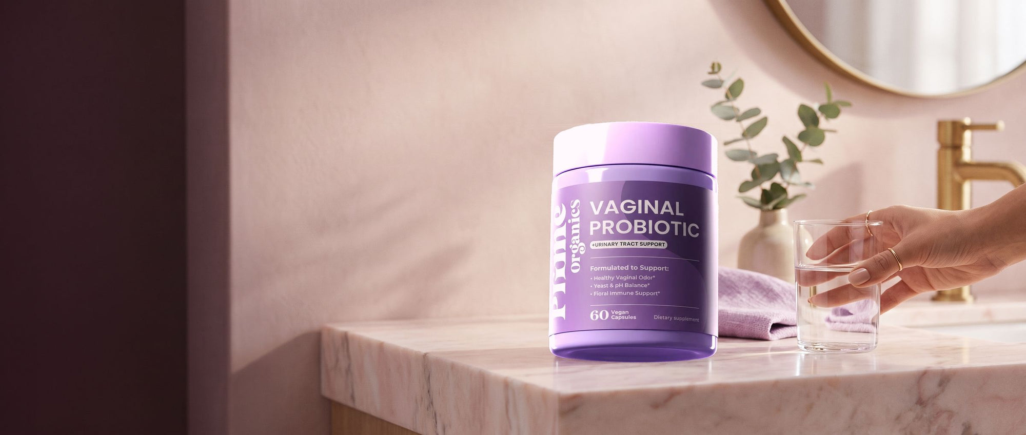 Prime Organics Vaginal Probiotic on a marble vanity beside a glass of water