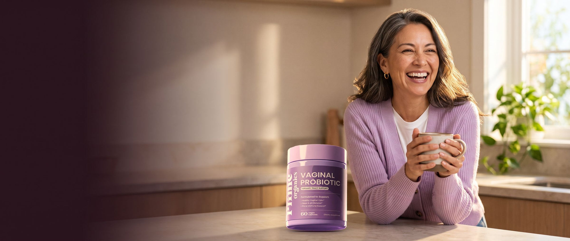 A woman in her late forties laughing over her morning coffee in a sunny kitchen, Prime Organics Vaginal Probiotic on the counter